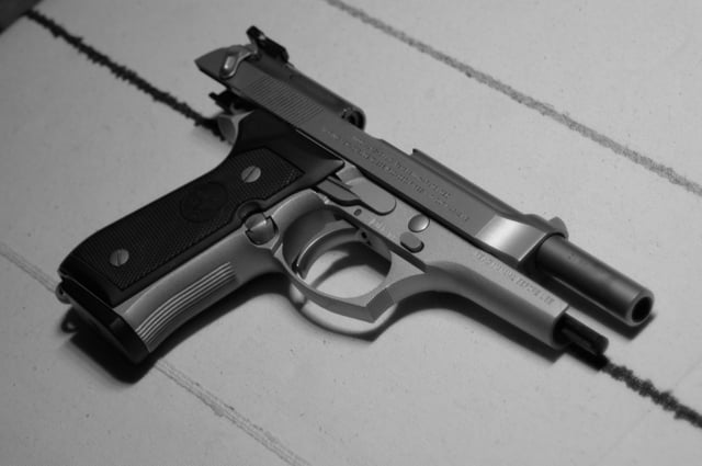 A Beretta 92FS Inox with the slide retracted, showing the exposed ejection port and barrel mechanism.