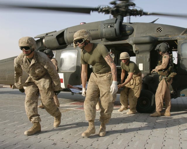 Marines unload a wounded comrade from an Army UH-60 Blackhawk helicopter for medical treatment at Al Qaim.