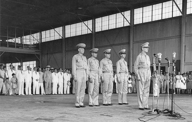 Ceremony at Camp Murphy, 15 August 1941, marking the induction of the Philippine Army Air Corps. Behind MacArthur, from left to right, are Lieutenant Colonel Richard K. Sutherland, Colonel Harold H. George, Lieutenant Colonel William F. Marquat and Major LeGrande A. Diller.