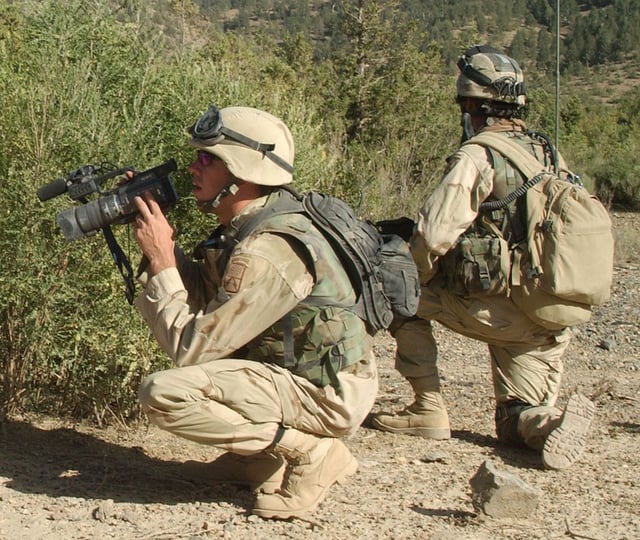A member of the Signal Corps shoots video of 10th Mountain Division soldiers as they search a mountainside near Shkin Firebase in late 2003.