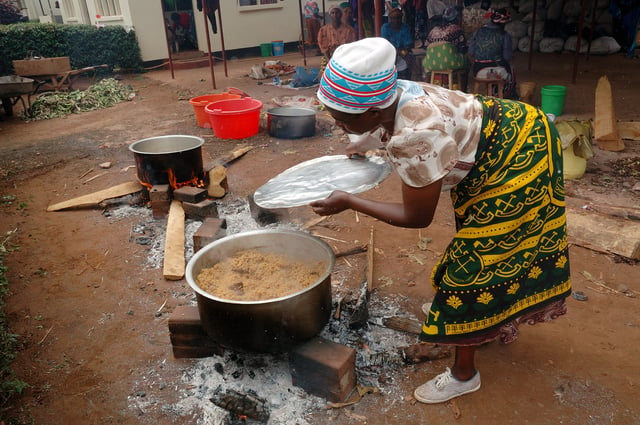 A Tanzanian woman cooks Pilau rice dish wearing traditional Kanga.