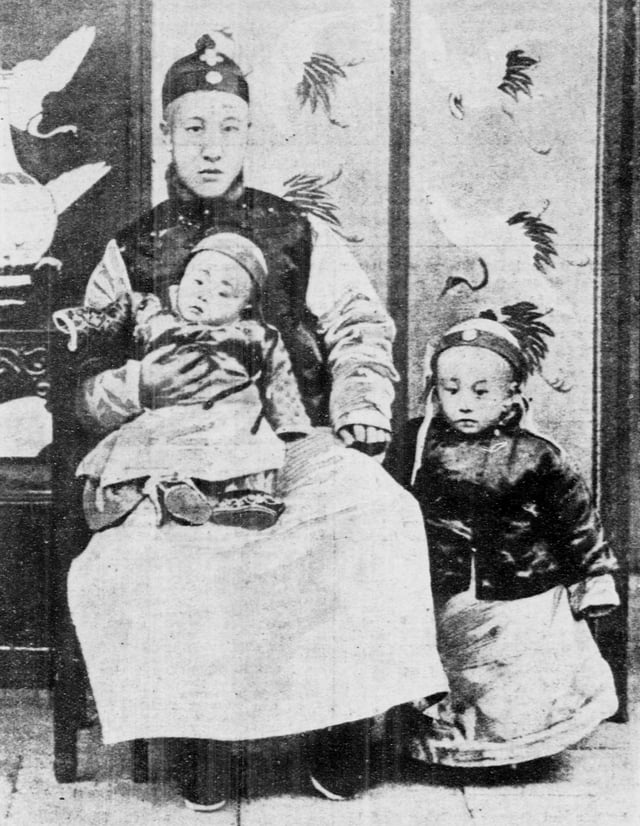 A three-year-old Puyi (right), standing next to his father (Zaifeng, Prince Chun) and his younger brother Pujie