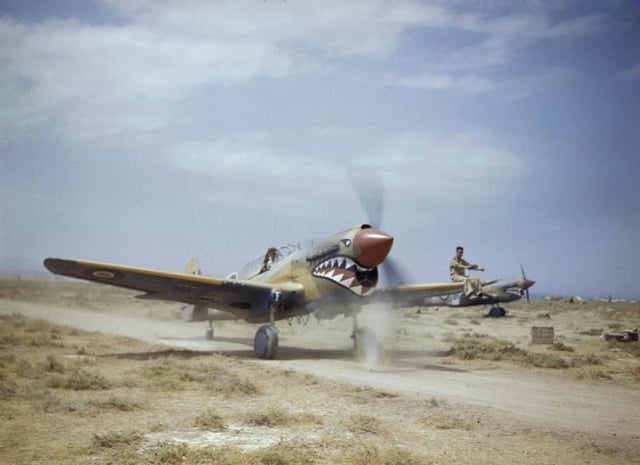 A Kittyhawk Mk III of No. 112 Squadron RAF, taxiing at Medenine, Tunisia, in 1943. A ground crewman on the wing is directing the pilot, whose view ahead is hindered by the aircraft's nose.