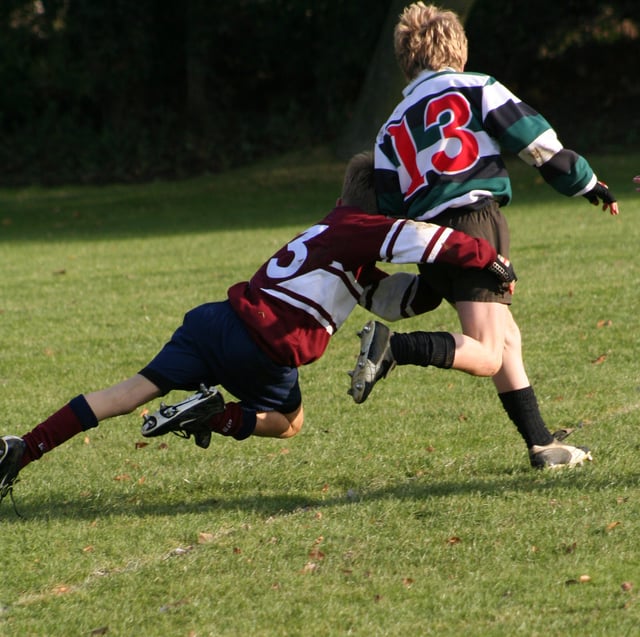 A rugby tackle: tackles must be below the neck with the aim of impeding or grounding the player with the ball