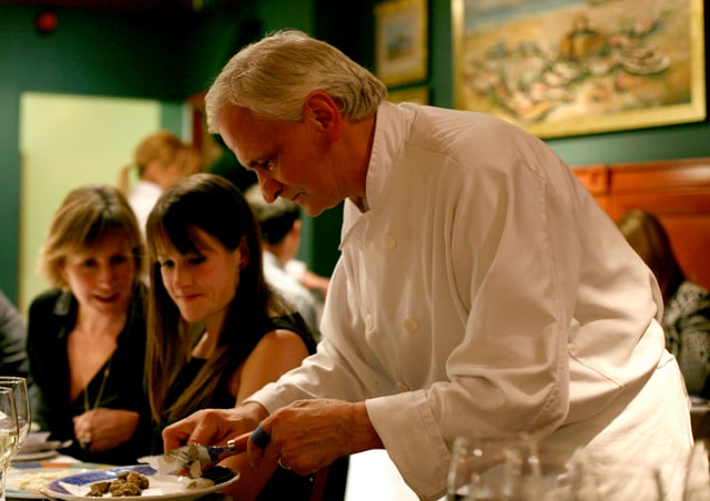 An Italian chef preparing a truffle for diners