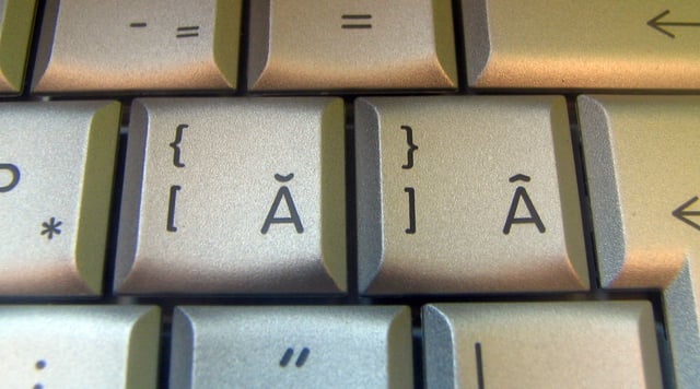 A close shot of some keys with Romanian characters on the keyboard of a laptop