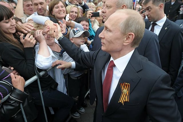 Putin, with St. George ribbon, greets local residents during a visit to the Crimean city of Sevastopol on 9 May 2014