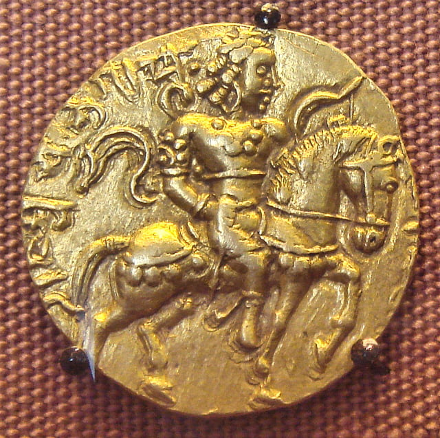 An 8 gm gold coin featuring Chandragupta II astride a caparisoned horse with a bow in his left hand