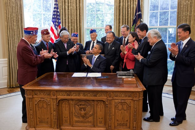 President Obama and his guests applaud after signing S.1055, a bill to grant the Congressional Gold Medal.