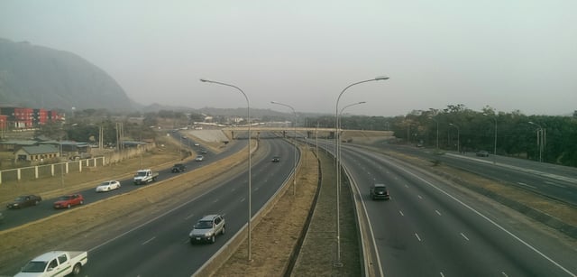 A view of a section of the Outer Northern Expressway, ONEX (Maitama Avenue intersection), with the IBB International Golf course to the right and the Nigerian Army Resource centre and Aso Rock to the left.