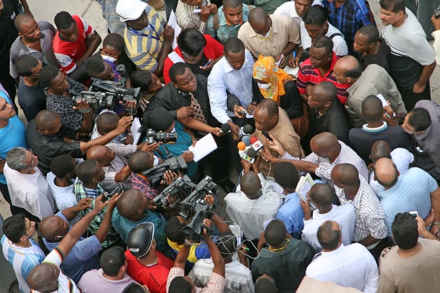 Photo and broadcast journalists interviewing a government official after a building collapse in Dar es Salaam, Tanzania. March 2013.