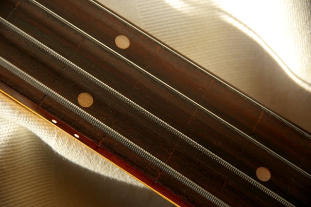 A fretless bass with flatwound strings; markers are inlaid into the side of the fingerboard, to aid the performer in finding the correct pitch.