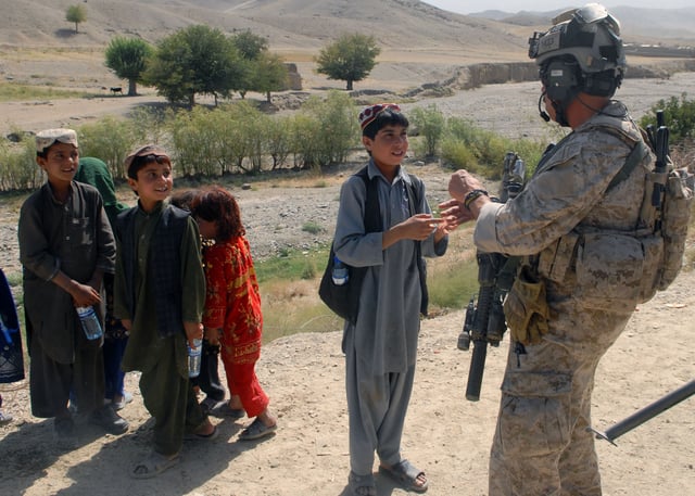A US Navy SEAL, assigned to Special Operations Task Force-South East, greets children in a village in Uruzgan Province, 30 August 2012.