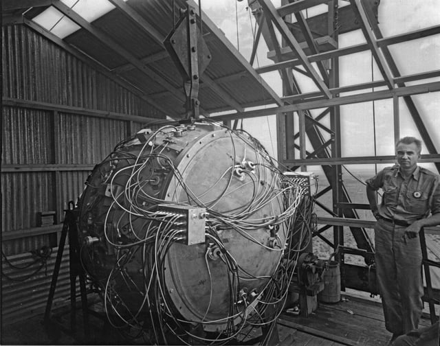 Norris Bradbury, group leader for bomb assembly, stands next to the assembled Gadget atop the test tower. Later, he became the director of Los Alamos, after the departure of Oppenheimer.