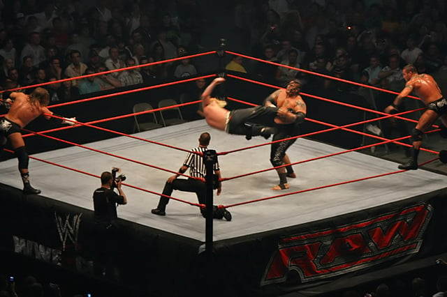 A tag team match in progress: Jeff Hardy kicks Umaga, while their respective partners, Triple H and Randy Orton, encourage them and reach for the tags