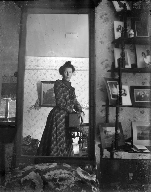 Unidentified woman taking her picture in a mirror, c. 1900