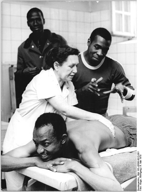 Massage trainer teaches sports students how to do massage (Leipzig, German Democratic Republic)