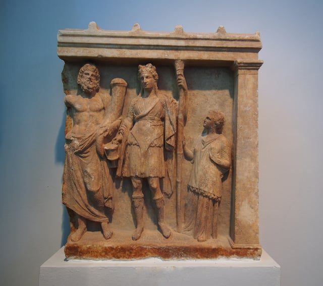 Votive relief of Dionysus and Pluto with adorant. 4th century BC. From Karystos, Archaeological museum of Chalkida.