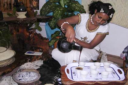 An Eritrean woman pouring traditionally brewed coffee from a jebena during a coffee ceremony