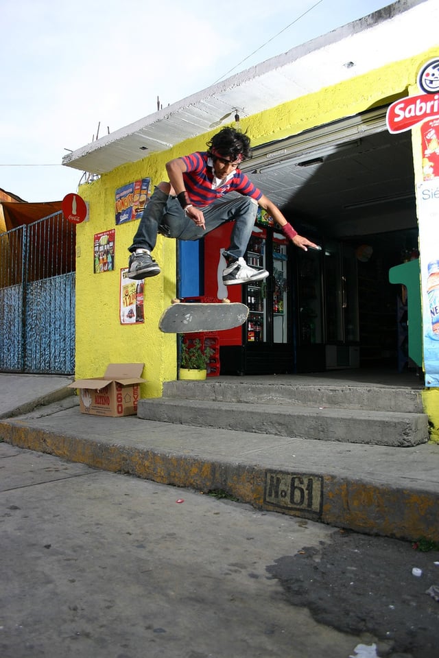 A skater performs a switch kickflip off a stairset.