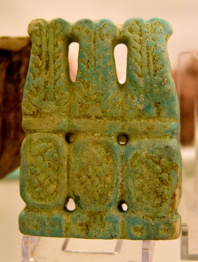 Stamp or thumb ring in the form of 3 cartouches (enclosing dot pattern). Each topped with 2 plumes and sun disc. Faience. From Meroe. Meroitic period. Petrie Museum of Egyptian Archaeology