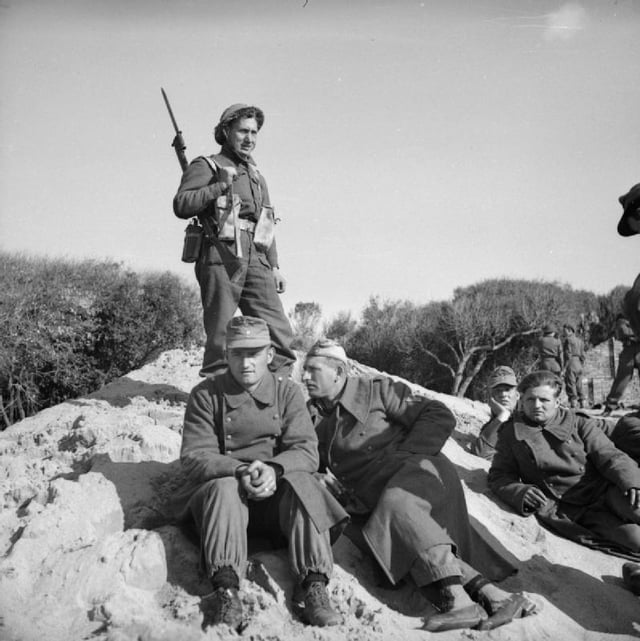 A British soldier guards a group of German prisoners at Anzio, 22 January 1944.