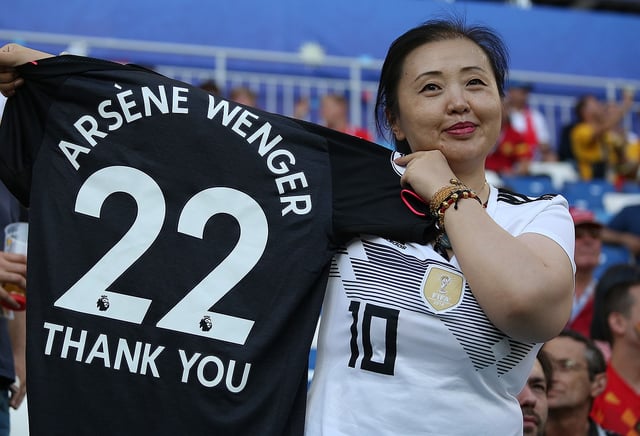 Fan holding an Arsenal shirt bearing the text "Arsène Wenger Thank You" at the match between Belgium and England at the 2018 FIFA World Cup