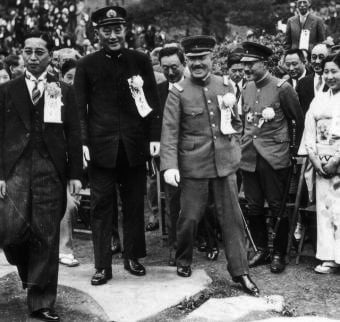 The newly appointed War Minister Itagaki (center, stepping down from the rock) with his vice-minister Hideki Tōjō (right) and Navy minister Mitsumasa Yonai (left, in black Navy uniform, standing on the rock)