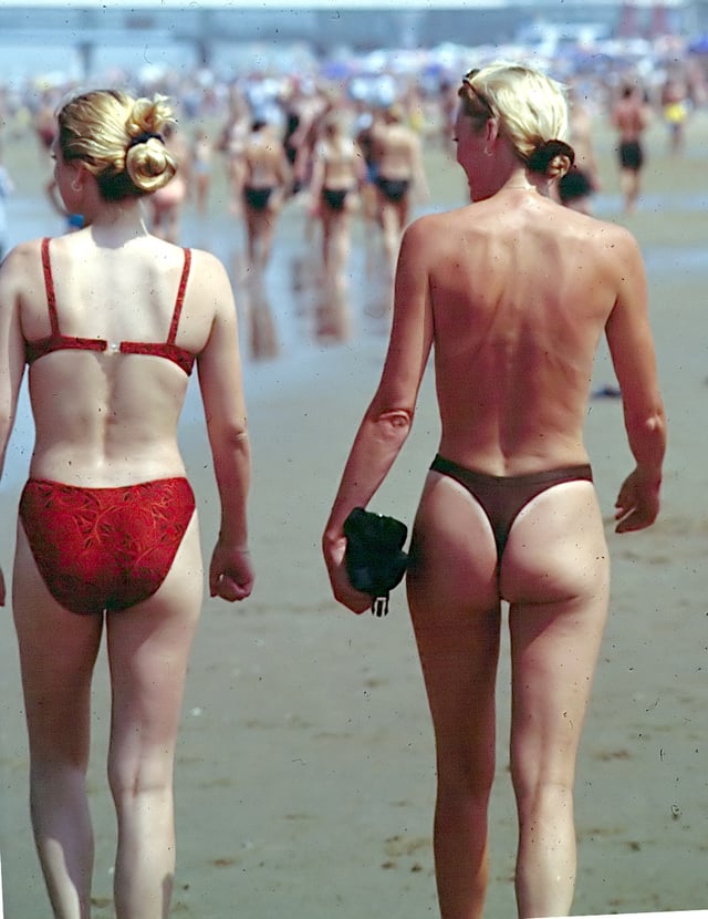 Some female clothing, such as the bikini or panties, show part of the female buttocks (girl on left). Thongs, in particular, leave almost all of the buttocks exposed (girl on right). Photo is of a beach in Holland, 1999.