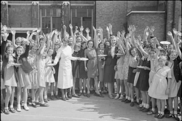 Food aid from America: British pupils wave for the camera as they receive plates of bacon and eggs.