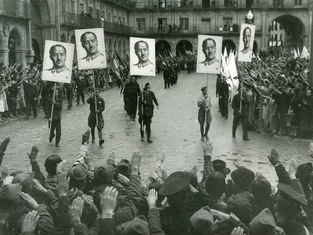 Francoist demonstration in Salamanca (1937) with the paraders carrying the portrait of Franco in banners and the populace pulling the fascist salute.