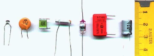 Capacitor materials. From left: multilayer ceramic, ceramic disc, multilayer polyester film, tubular ceramic, polystyrene, metalized polyester film, aluminum electrolytic. Major scale divisions are in centimetres.