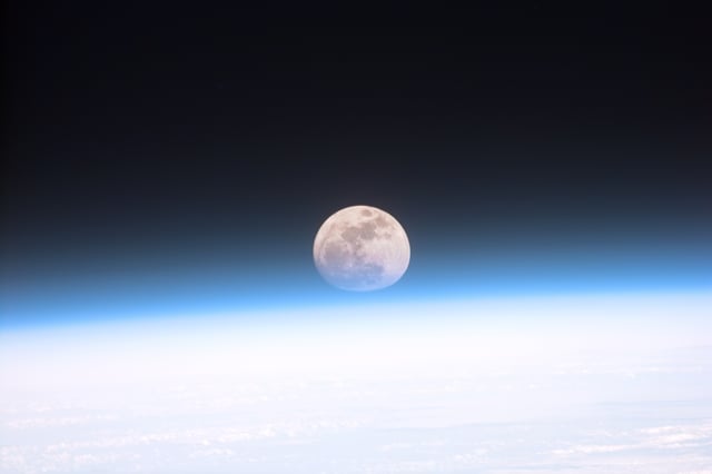 This view from orbit shows the Full moon partially obscured by Earth's atmosphere.