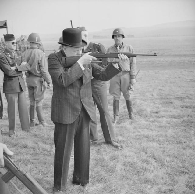 Churchill fires an American M1 carbine during a visit to the US 2nd Armored Division on Salisbury Plain, 23 March 1944.