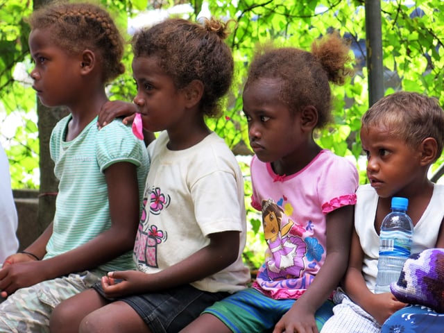 Children in Solomon Islands watch a play on gender-based violence