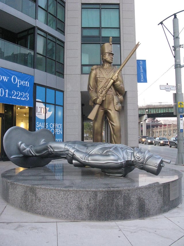 Douglas Coupland's 'Monument to the War of 1812' (2008) in Toronto; depicts a larger-than-life Canadian soldier triumphing over an American; both are depicted as metallic toy soldiers of the sort small children play with.