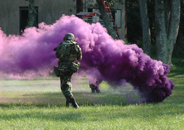 A violet signaling smoke grenade being used during a military training exercise