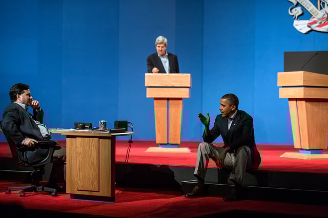 President Obama talks with Ron Klain during presidential debate preparations. Senator John Kerry, at podium, played the role of Mitt Romney during the preparatory sessions.