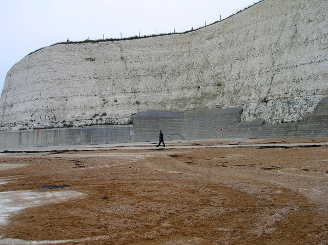 To the east of Brighton, chalk cliffs protected by a sea-wall rise from the beach.