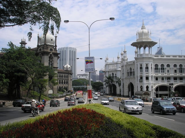The Kuala Lumpur Railway Station (right) contrasts with a Keretapi Tanah Melayu (left) Administration Building darker, similarly Mughal-styled building. Both designed by A. B. Hubback