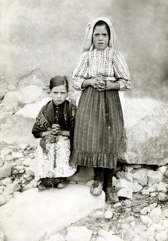 Lúcia dos Santos (standing) with her cousin, Jacinta Marto, 1917