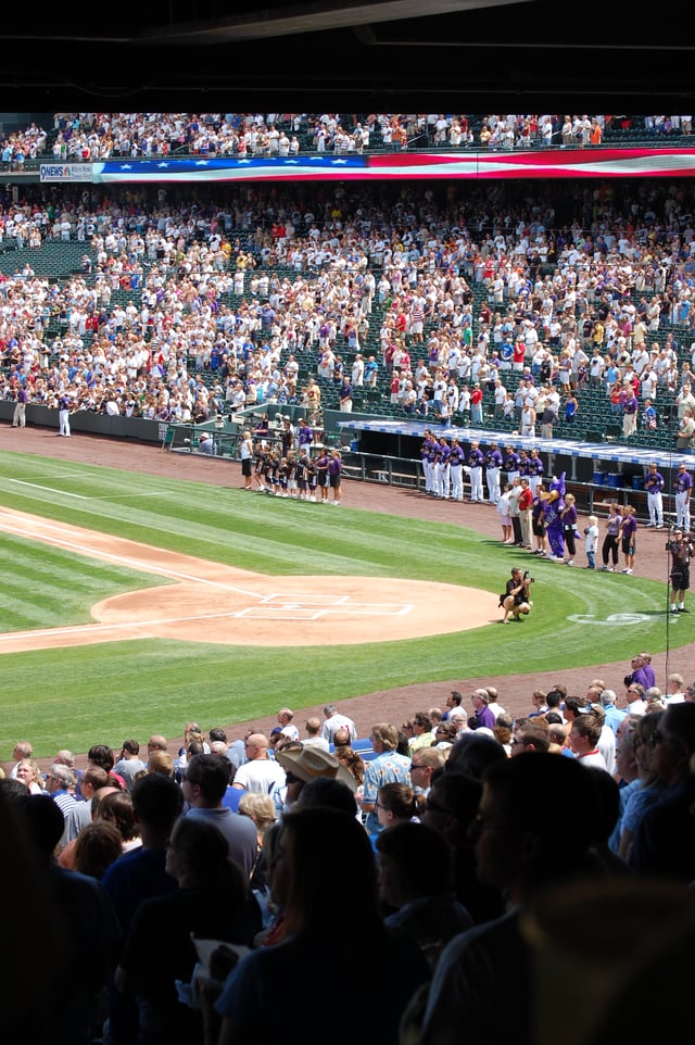 Crowd performing the U.S. national anthem before a baseball game at Coors Field