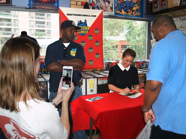 As actress Alyssa Milano autographs copies of her graphic novel during an appearance at Midtown Comics in Manhattan, her assistant, Kelly Kall (left foreground) streams video of the event on Periscope.
