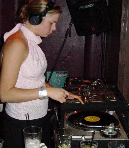 A DJ mixing two record players at a live event.