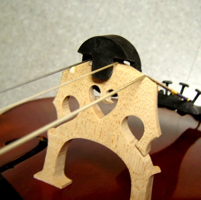 A modern mute on the bridge of a cello