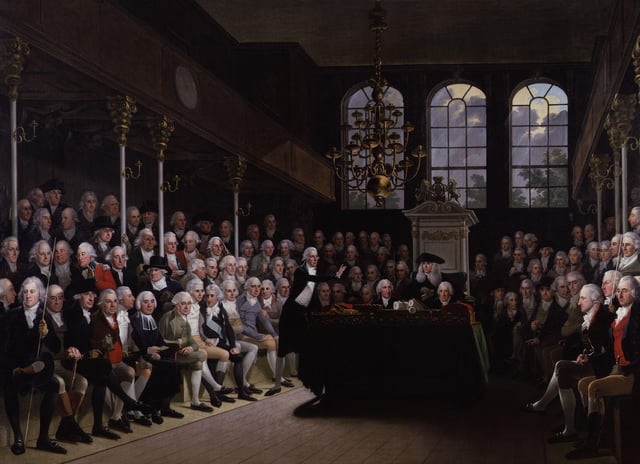 William Pitt the Younger addressing the House of Commons. Pitt's 19 years as Prime Minister followed by Lord Liverpool's 15, led the Tory Party to accept the office as a convention of the constitution.