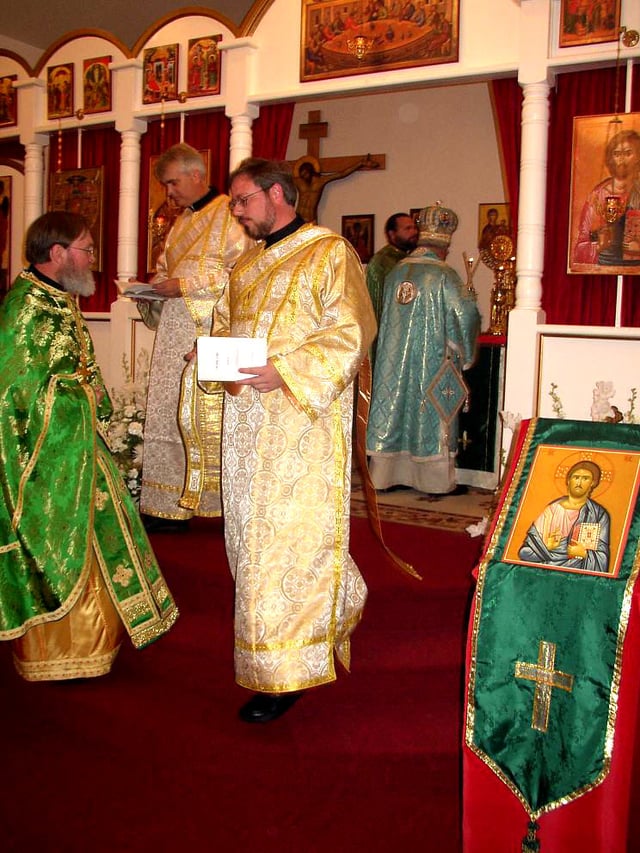 Orthodox Christian clergy: bishop (right, at altar), priest (left), and two deacons (in gold)