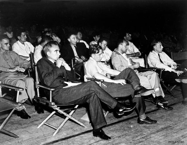 Physicists at a Manhattan District-sponsored colloquium at the Los Alamos Laboratory on the Super in April 1946. In the front row are Norris Bradbury, John Manley, Enrico Fermi and J. M. B. Kellogg. Robert Oppenheimer, in dark coat, is behind Manley; to Oppenheimer's left is Richard Feynman. The Army officer on the left is Colonel Oliver Haywood.