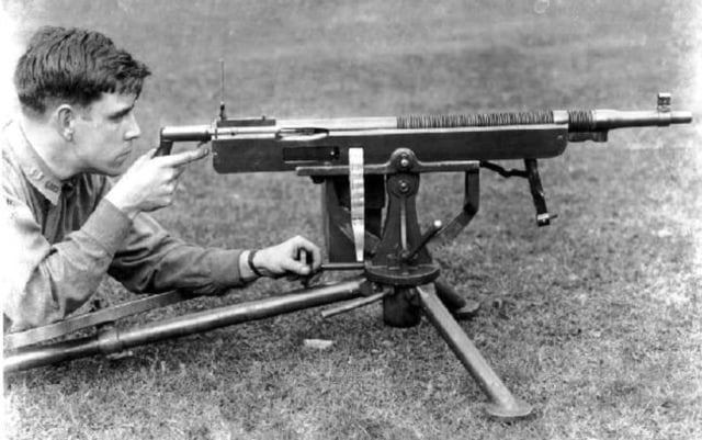 One of the later versions of the Colt-Browning M1895 machine gun is demonstrated by a US Army operator. The gun is shown mid-action, with the operating lever extending downward below the front of the barrel.