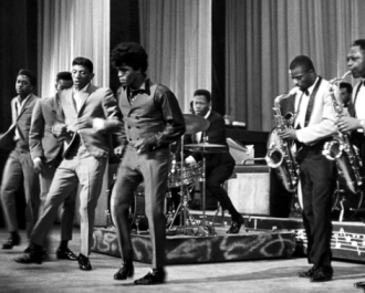 Brown (middle) and The Famous Flames (far left to right, Bobby Bennett, Lloyd Stallworth, and Bobby Byrd), performing live at the Apollo Theater in New York City, 1964